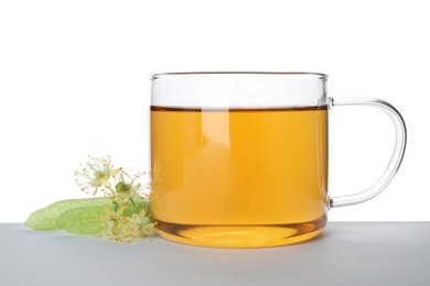 Photo of Tasty linden tea in cup, leaves and flowers isolated on white