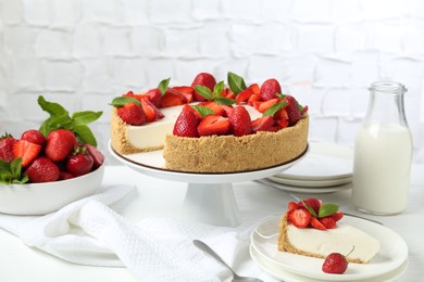 Photo of Delicious cheesecake with strawberries, mint and milk on white wooden table