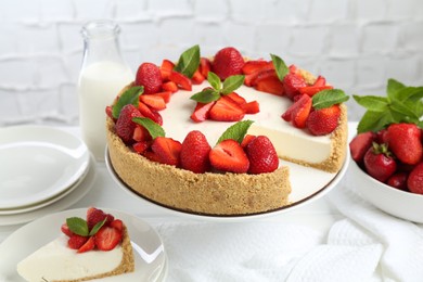 Photo of Delicious cheesecake with strawberries, mint and milk on table, closeup