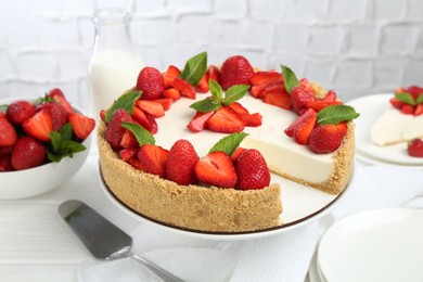 Photo of Delicious cheesecake with strawberries and mint on white wooden table, closeup