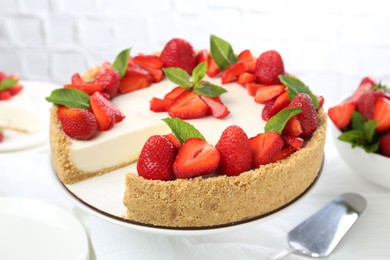 Photo of Delicious cheesecake with strawberries and mint on white table, closeup