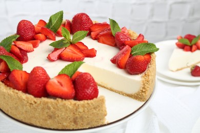 Photo of Delicious cheesecake with strawberries and mint on table, closeup