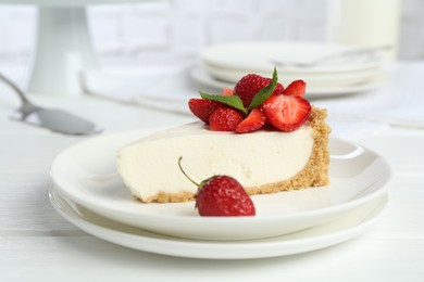 Photo of Piece of tasty cheesecake with strawberries and mint on white wooden table, closeup