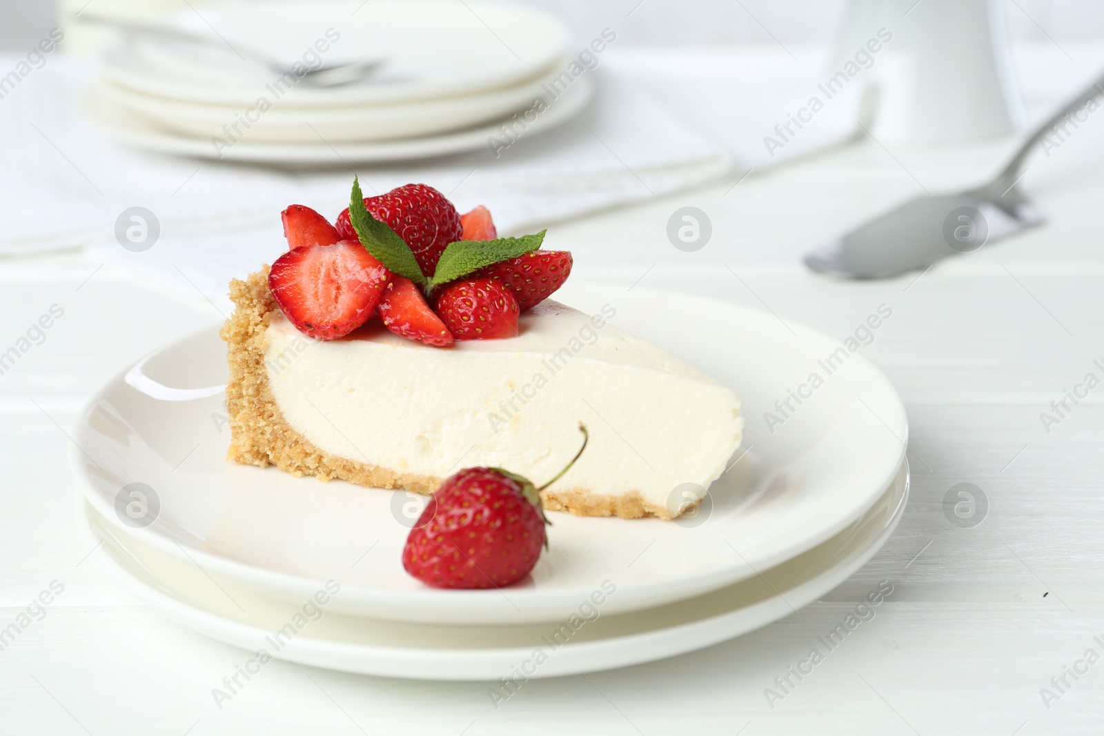Photo of Piece of tasty cheesecake with strawberries and mint on white wooden table, closeup