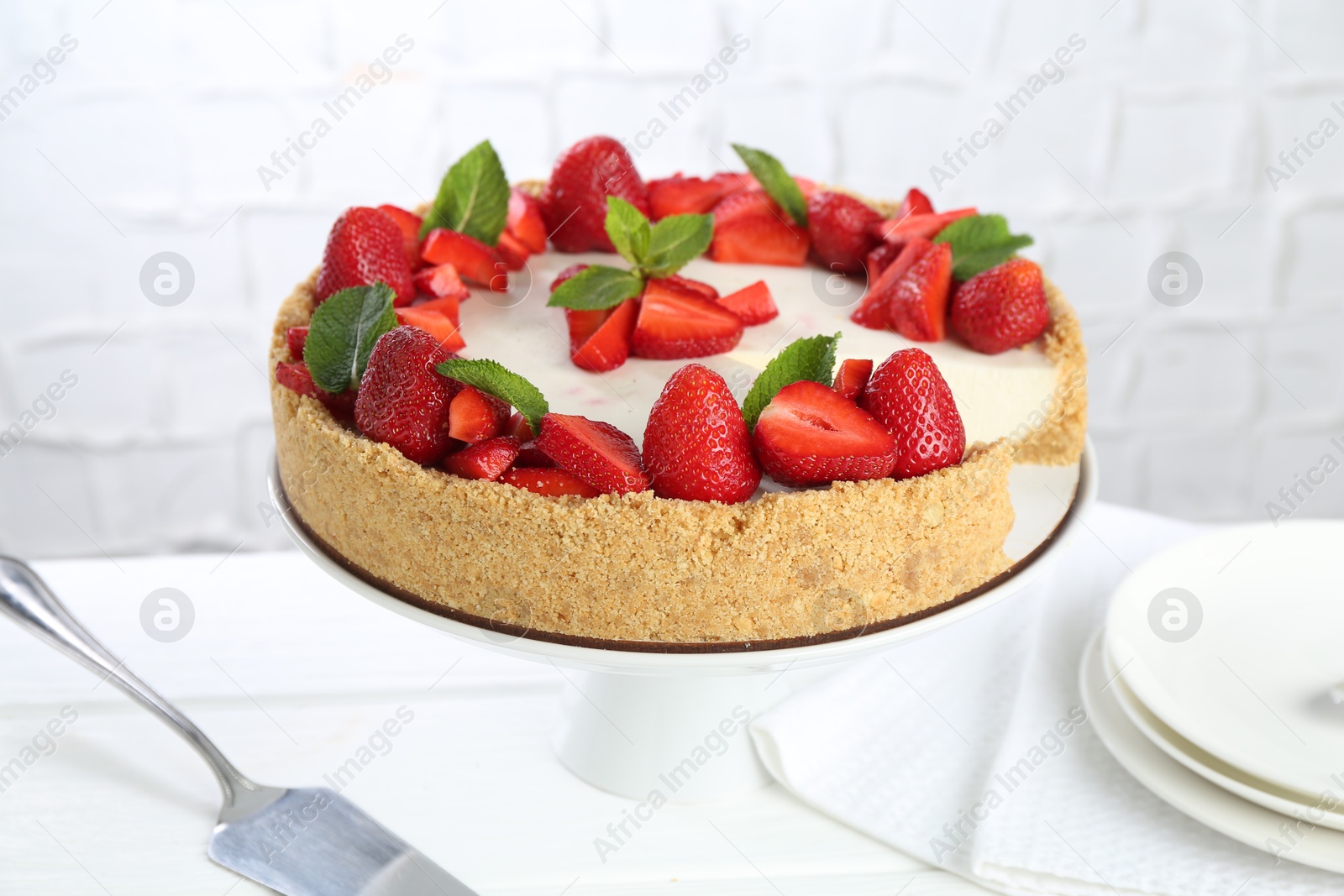Photo of Delicious cheesecake with strawberries and mint on white wooden table, closeup