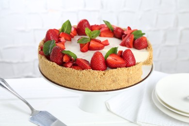 Photo of Delicious cheesecake with strawberries and mint on white wooden table, closeup