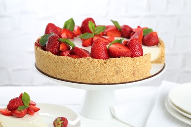 Photo of Delicious cheesecake with strawberries and mint on white table, closeup