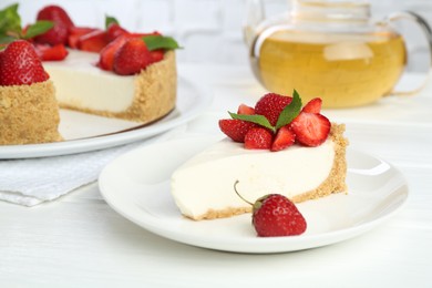 Photo of Piece of tasty cheesecake with strawberries, mint and tea on white wooden table, closeup