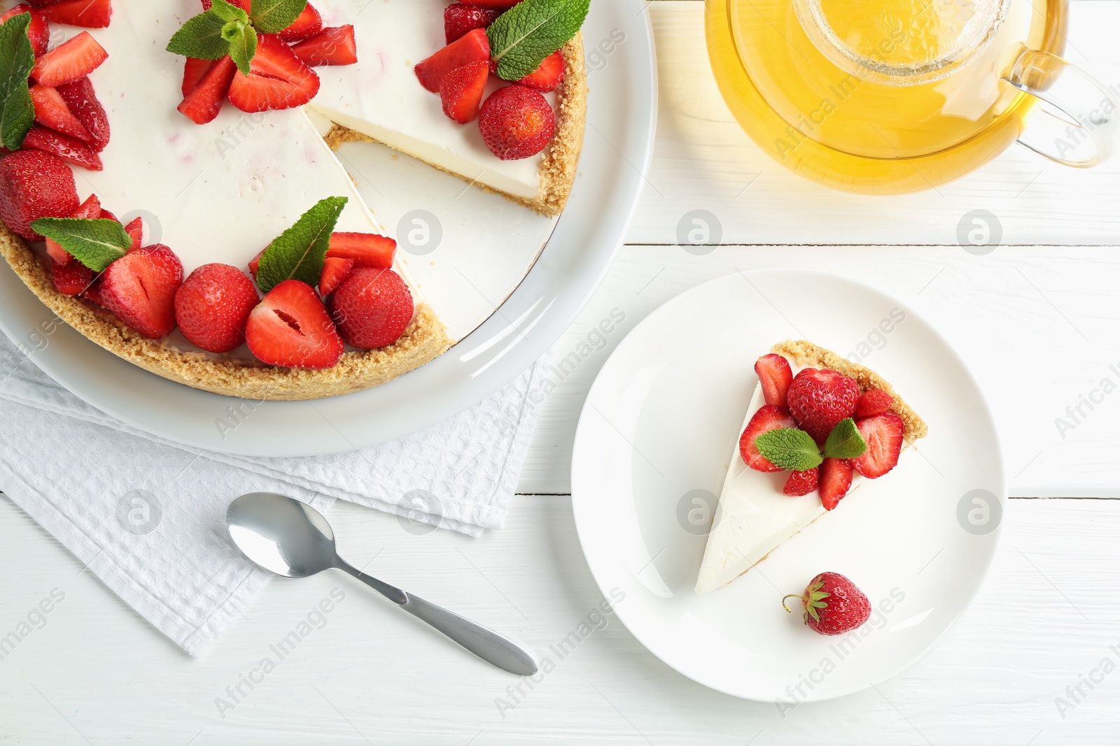 Photo of Delicious cheesecake with strawberries, mint and tea on white wooden table, flat lay