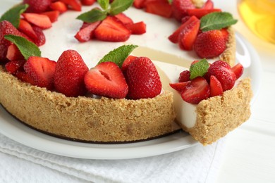 Photo of Delicious cheesecake with strawberries and mint on white table, closeup