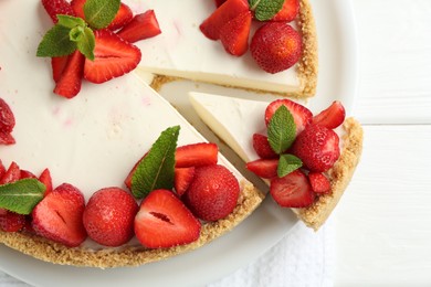 Photo of Delicious cheesecake with strawberries and mint on white wooden table, top view