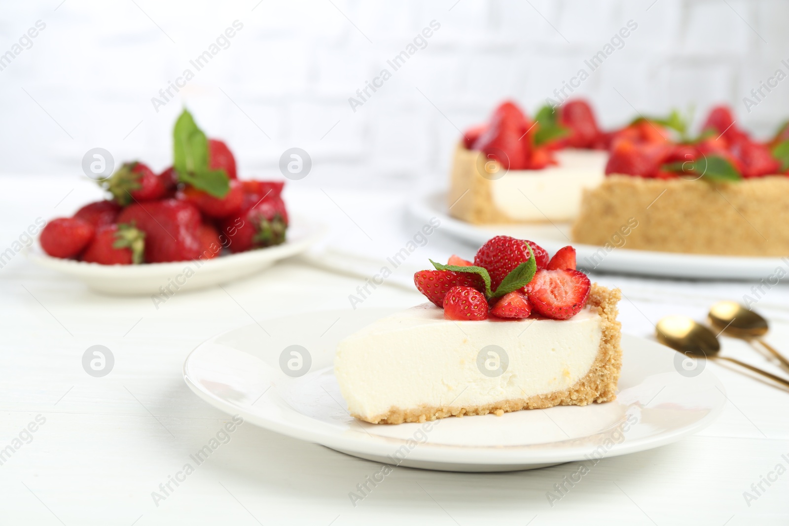 Photo of Piece of tasty cheesecake with strawberries and mint on white wooden table, closeup