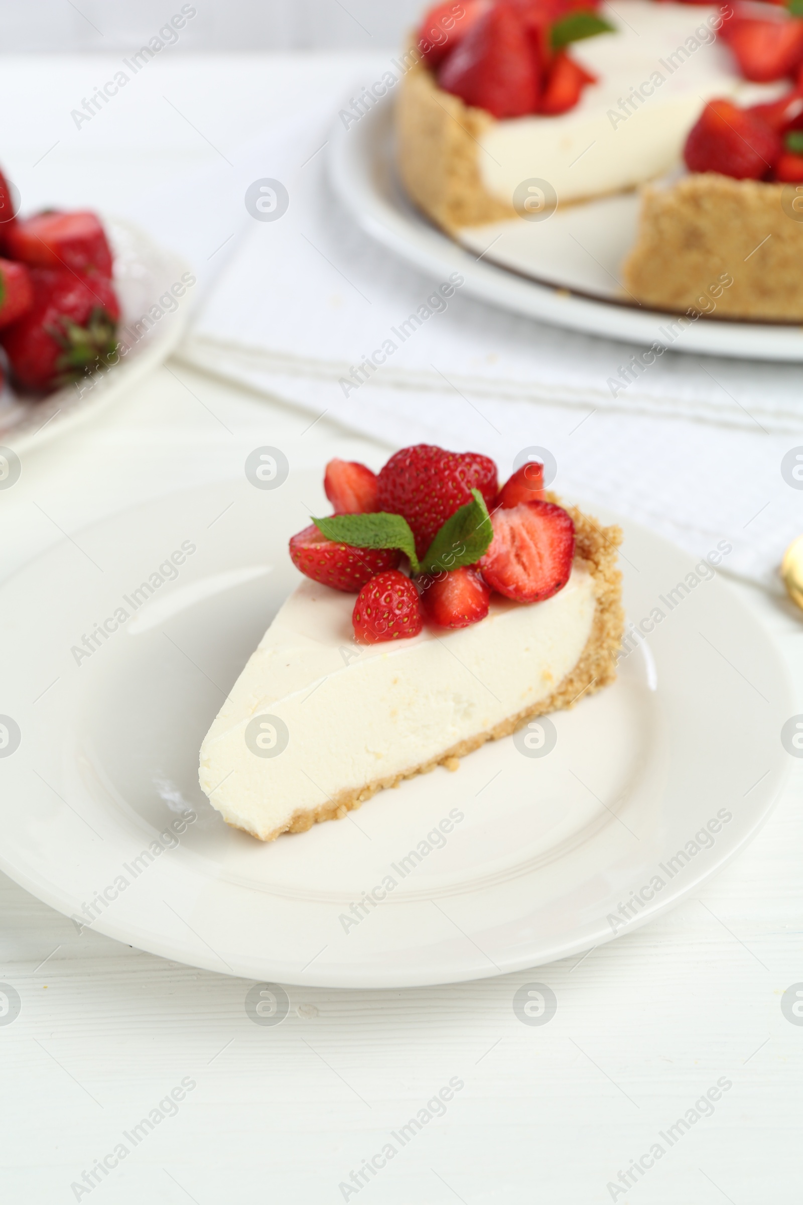 Photo of Piece of tasty cheesecake with strawberries and mint on white wooden table, closeup