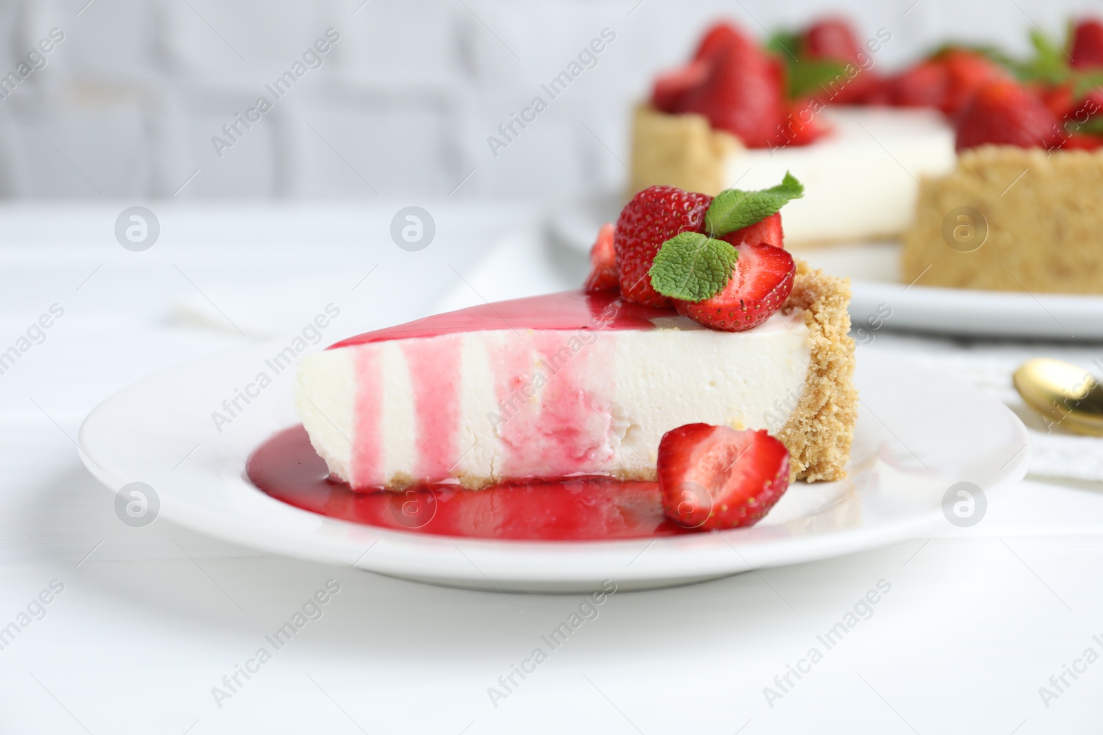 Photo of Piece of tasty cheesecake with strawberries, sauce and mint on white wooden table, closeup