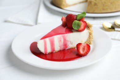 Photo of Piece of tasty cheesecake with strawberries, sauce and mint on white wooden table, closeup