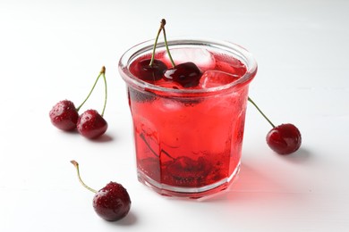 Photo of Tasty cherry soda with ice cubes and berries on white wooden table, closeup