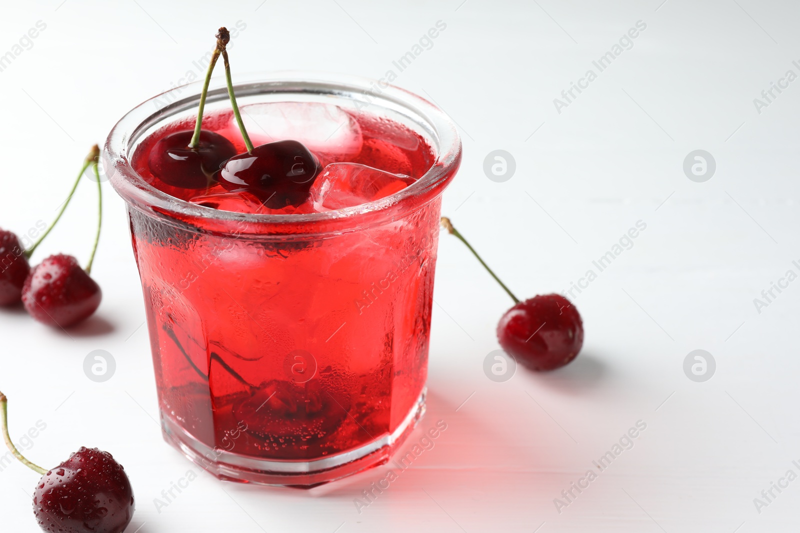 Tasty cherry soda with ice cubes and berries on white wooden table, closeup. Space for text Photo of Tasty cherry soda with ice cubes and berries on white wooden table, closeup. Space for text