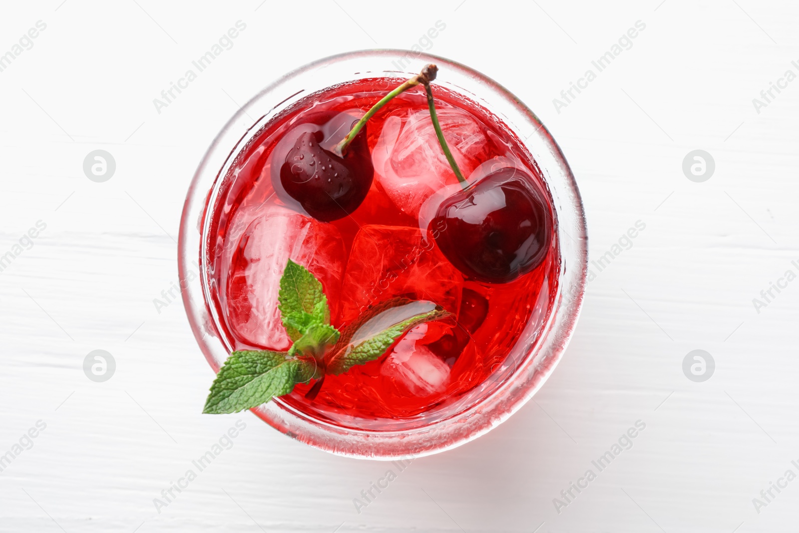 Tasty cherry soda with ice cubes, mint and berries on white wooden table, top view Photo of Tasty cherry soda with ice cubes, mint and berries on white wooden table, top view