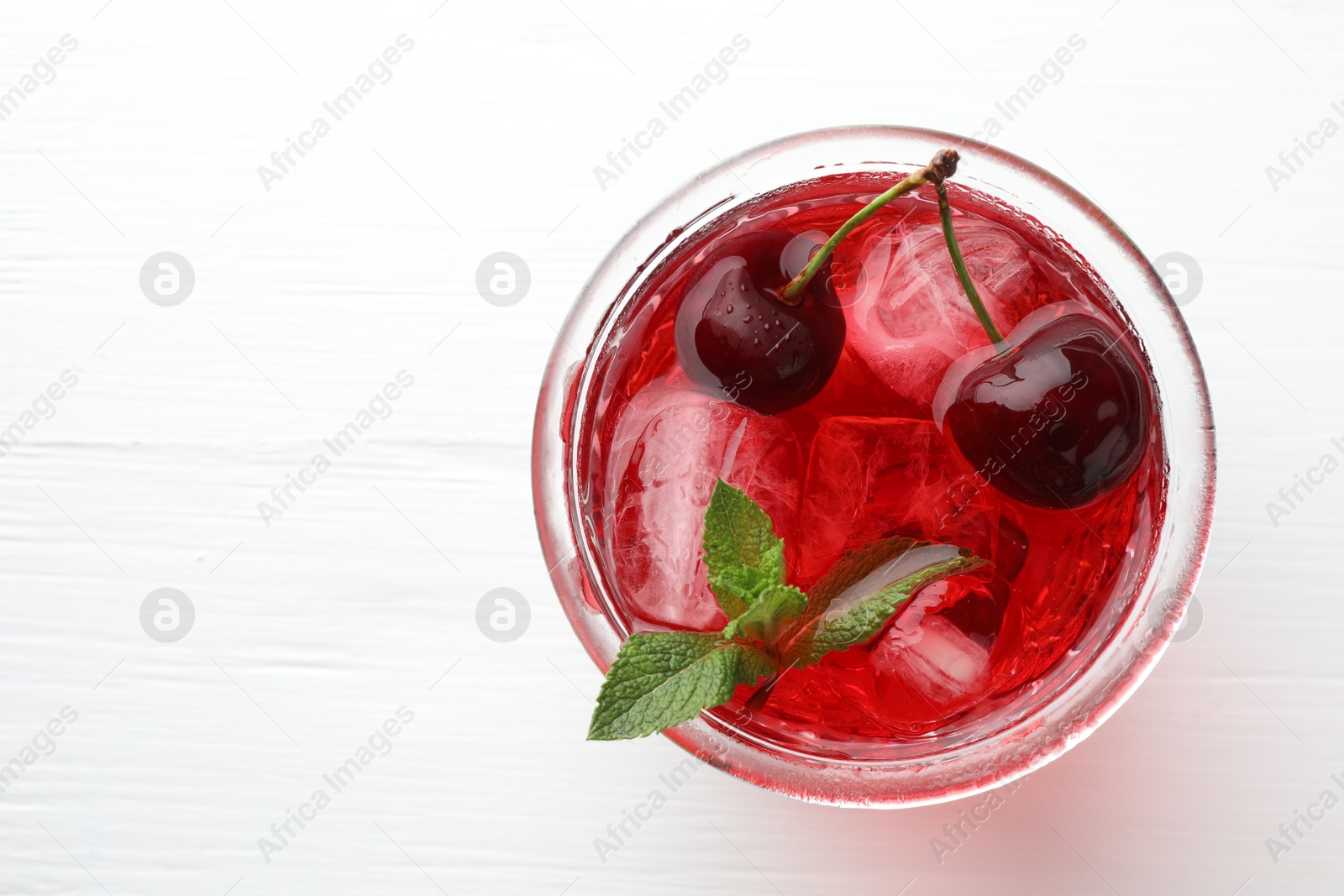 Tasty cherry soda with ice cubes, mint and berries on white wooden table, top view. Space for text Photo of Tasty cherry soda with ice cubes, mint and berries on white wooden table, top view. Space for text