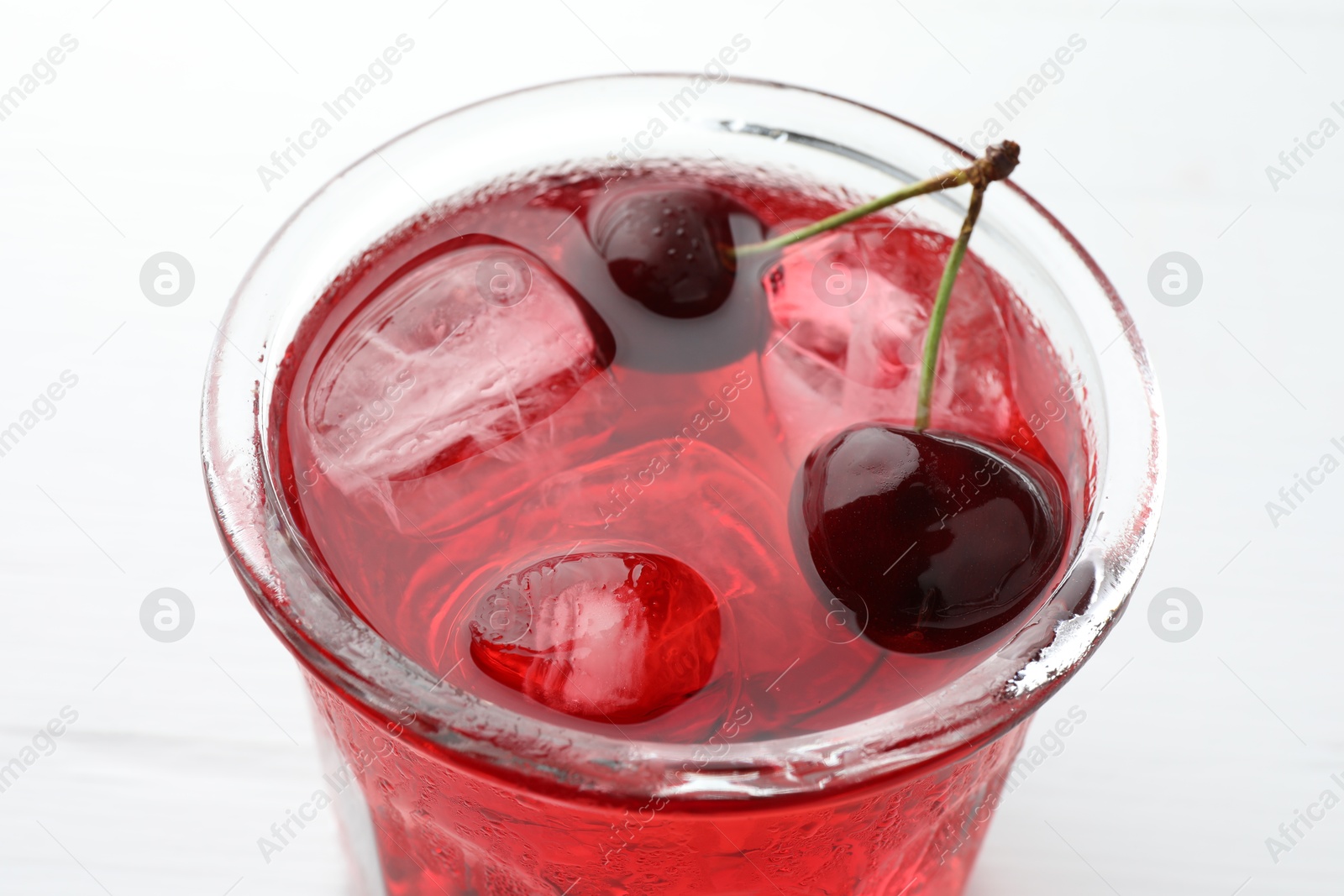 Tasty cherry soda with ice cubes and berries on white wooden table, closeup Photo of Tasty cherry soda with ice cubes and berries on white wooden table, closeup