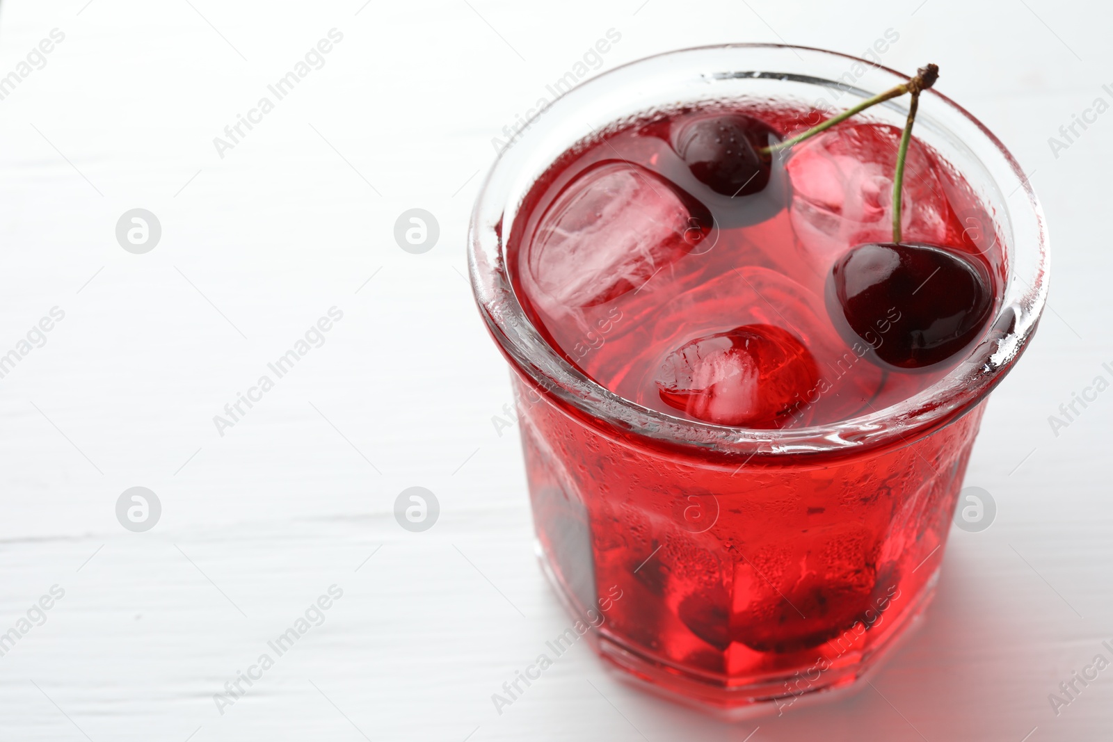Tasty cherry soda with ice cubes and berries on white wooden table, closeup. Space for text Photo of Tasty cherry soda with ice cubes and berries on white wooden table, closeup. Space for text