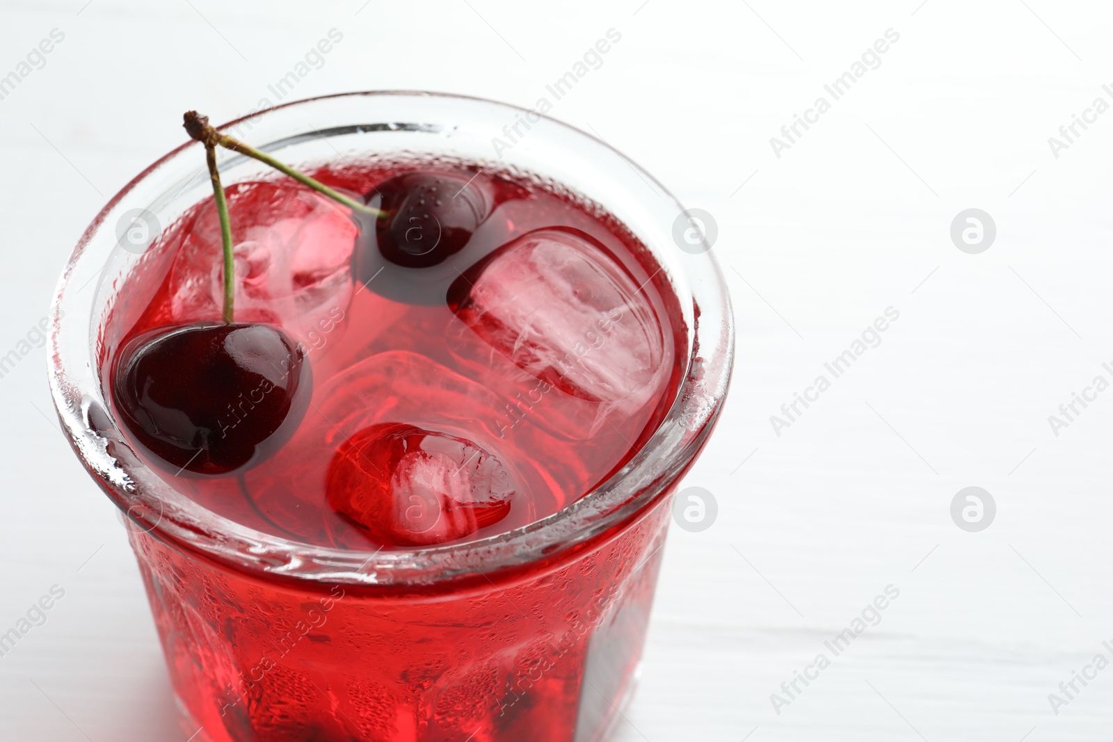 Tasty cherry soda with ice cubes and berries on white wooden table, closeup. Space for text Photo of Tasty cherry soda with ice cubes and berries on white wooden table, closeup. Space for text