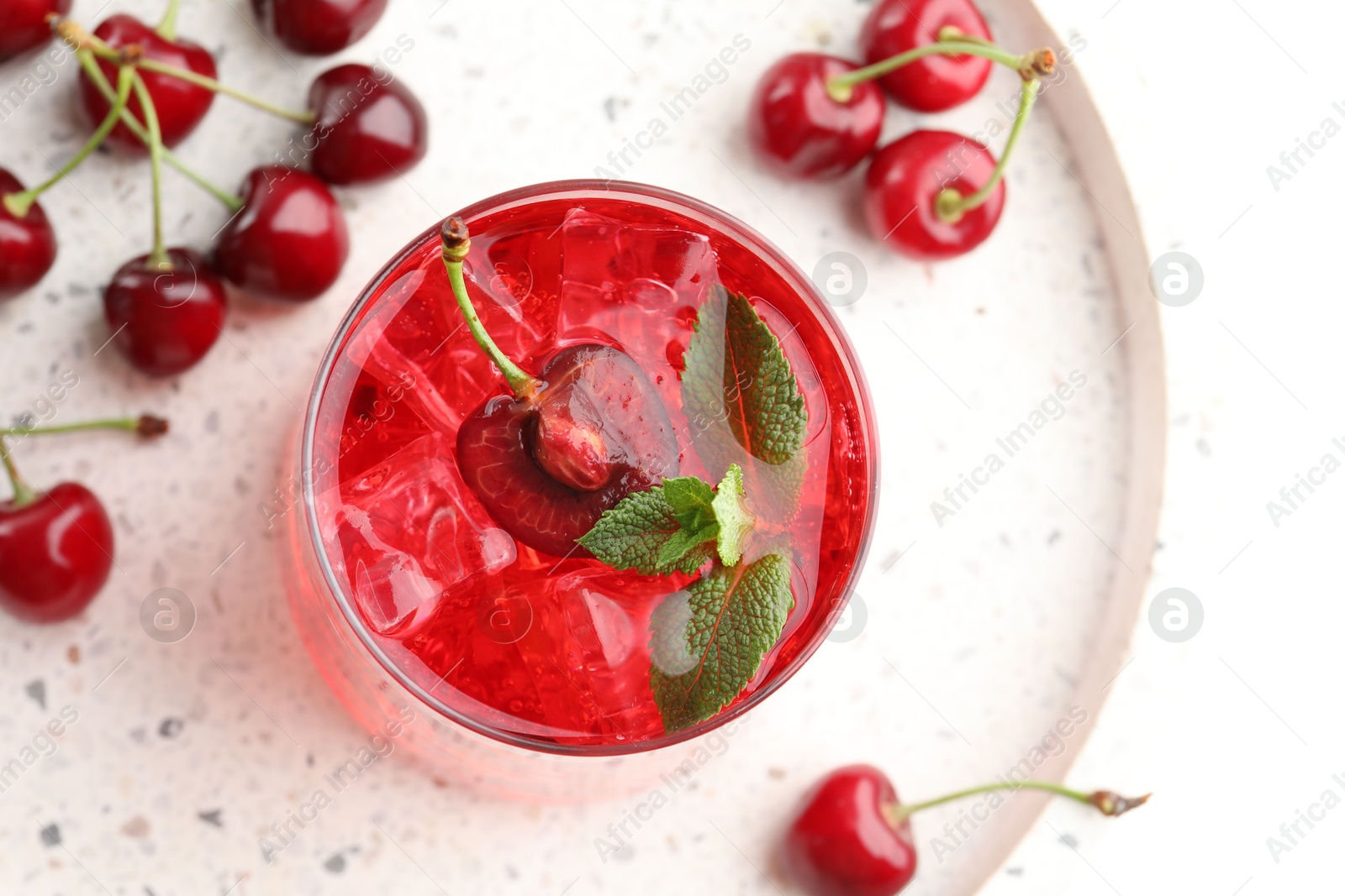 Tasty cherry soda with ice cubes, mint and berries on white table, flat lay Photo of Tasty cherry soda with ice cubes, mint and berries on white table, flat lay