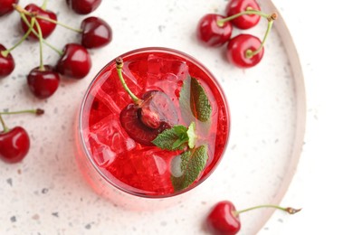 Photo of Tasty cherry soda with ice cubes, mint and berries on white table, flat lay
