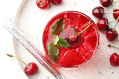 Photo of Tasty cherry soda with ice cubes, mint and berries on white table, flat lay