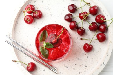 Photo of Tasty cherry soda with ice cubes, mint and berries on white wooden table, flat lay