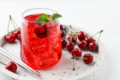 Photo of Tasty cherry soda with ice cubes, mint and berries on white wooden table, closeup