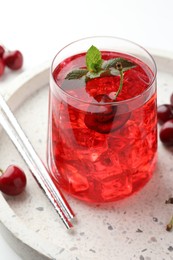 Photo of Tasty cherry soda with ice cubes, mint and berries on white table, closeup