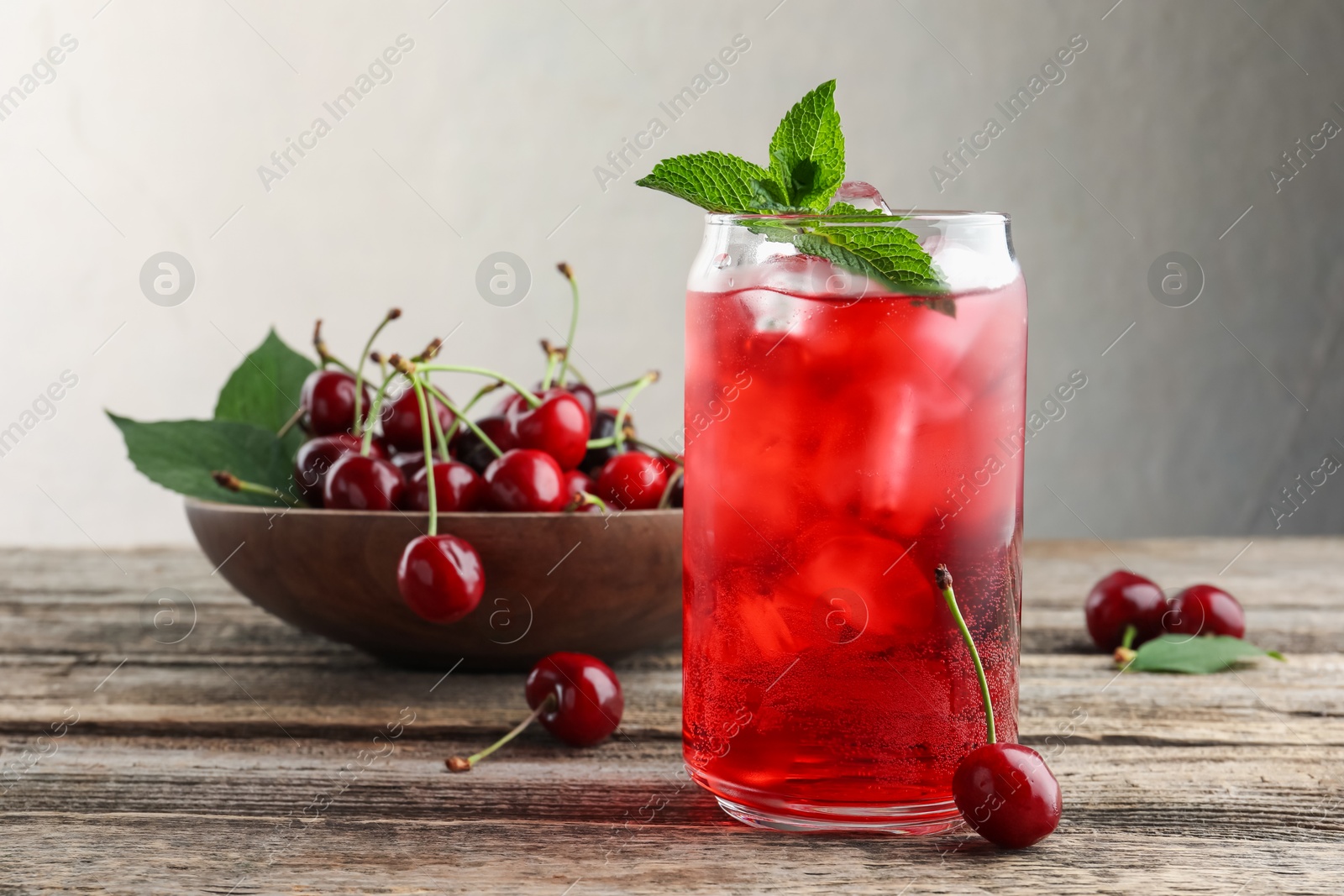 Tasty cherry soda with ice cubes, berries and mint on wooden table, closeup Photo of Tasty cherry soda with ice cubes, berries and mint on wooden table, closeup