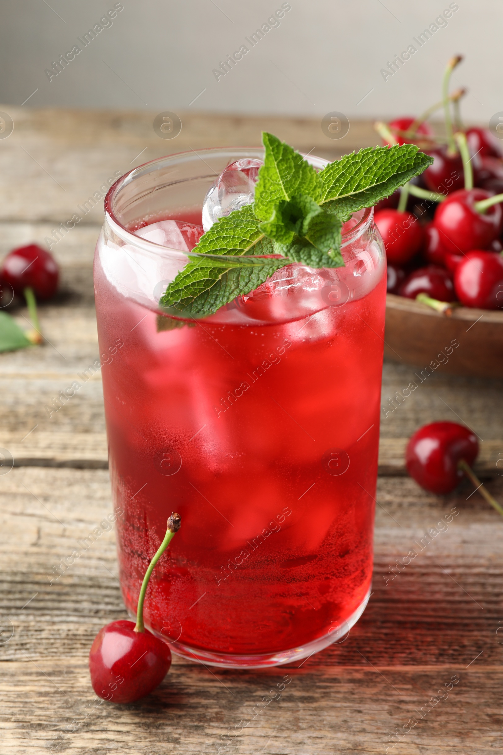 Tasty cherry soda with ice cubes, berries and mint on wooden table, closeup Photo of Tasty cherry soda with ice cubes, berries and mint on wooden table, closeup