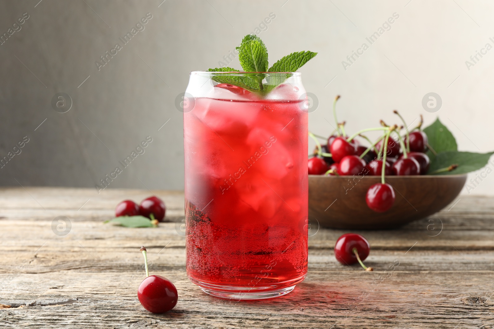 Tasty cherry soda with ice cubes, berries and mint on wooden table, closeup Photo of Tasty cherry soda with ice cubes, berries and mint on wooden table, closeup