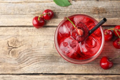 Photo of Tasty cherry soda with ice cubes and berries on wooden table, flat lay. Space for text