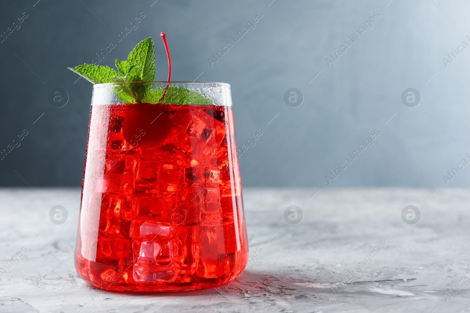 Tasty cherry soda with ice cubes and berry on grey textured table, closeup. Space for text Photo of Tasty cherry soda with ice cubes and berry on grey textured table, closeup. Space for text