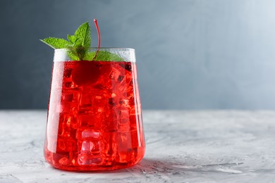 Photo of Tasty cherry soda with ice cubes and berry on grey textured table, closeup. Space for text