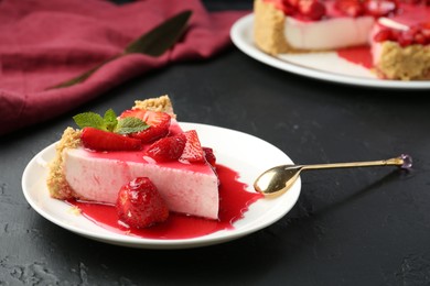 Photo of Piece of tasty cheesecake with strawberries, sauce and mint on black table, closeup
