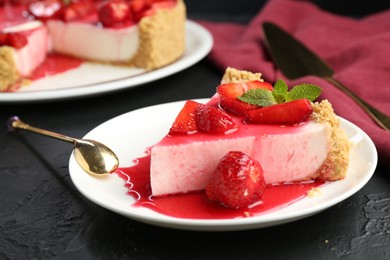 Photo of Piece of tasty cheesecake with strawberries, sauce and mint on black table, closeup