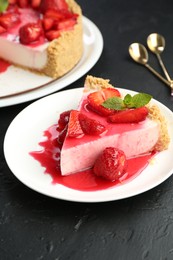 Photo of Piece of tasty cheesecake with strawberries, sauce and mint on black table, closeup