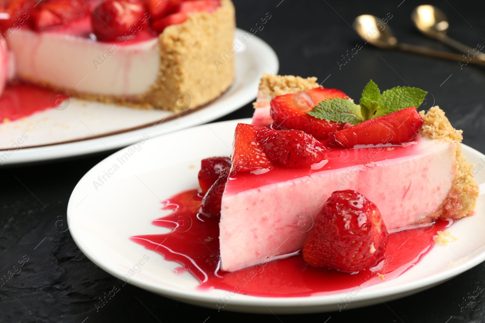 Photo of Piece of tasty cheesecake with strawberries, sauce and mint on black table, closeup