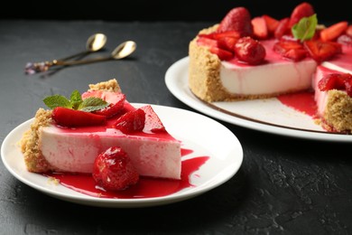 Photo of Delicious cheesecake with strawberries, sauce and mint on black table, closeup