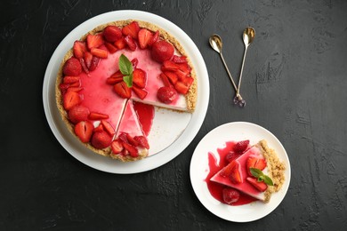 Photo of Delicious cheesecake with strawberries, sauce and mint on black table, flat lay
