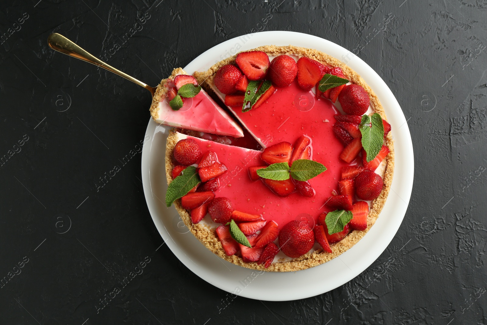 Photo of Delicious cheesecake with strawberries, sauce and mint on black table, top view