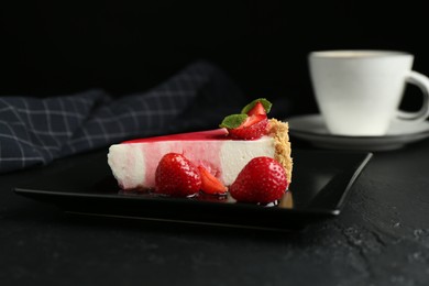 Photo of Piece of tasty cheesecake with strawberries, sauce, mint and coffee on black table, closeup
