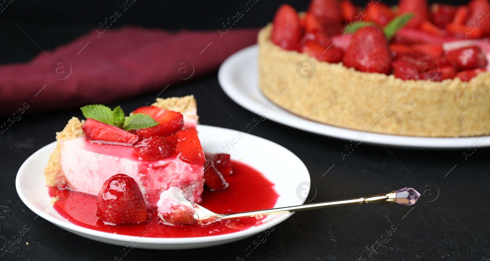 Photo of Delicious cheesecake with strawberries, sauce and mint on black table, closeup