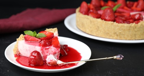 Photo of Delicious cheesecake with strawberries, sauce and mint on black table, closeup