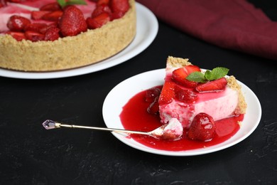 Photo of Delicious cheesecake with strawberries, sauce and mint on black table, closeup