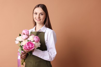Photo of Florist with beautiful bouquet of peonies on dark beige background, space for text